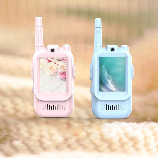 Pink and blue rechargeable video walkie talkies for kids standing side by side on a soft indoor surface